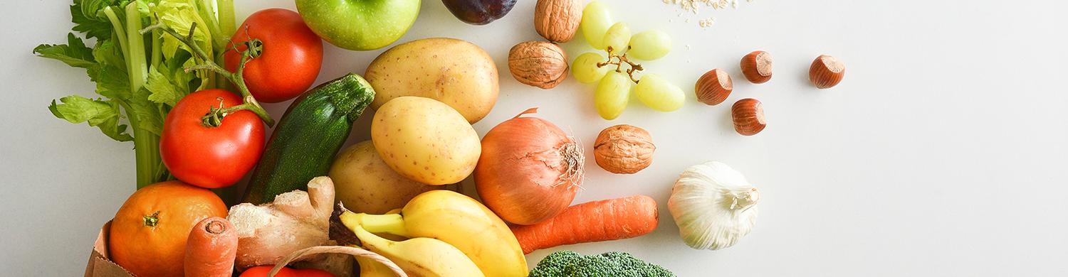 un sac en papier rempli de fruits et légumes sur fond blanc