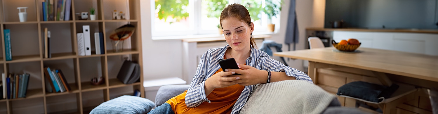 une adolescente sur son téléphone assise dans un canapé