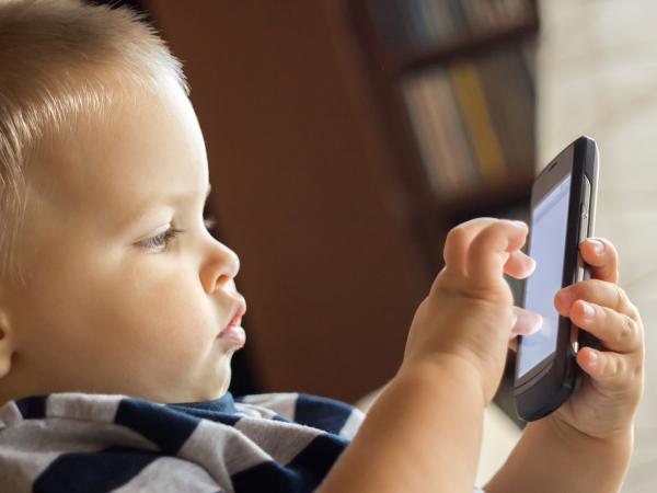 un jeune enfant joue sur un téléphone portable