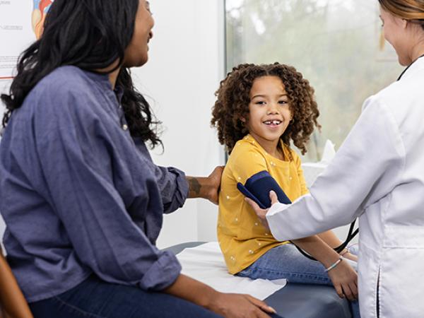 Un médecin qui prend la tension d’un enfant accompagné de sa mère