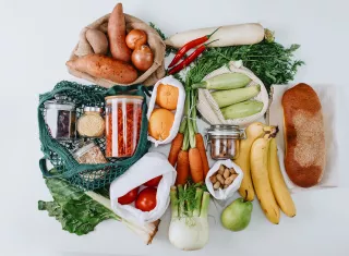 Des sacs et bocaux de fruits, légumes et graines sont présentés sur un fond blanc.