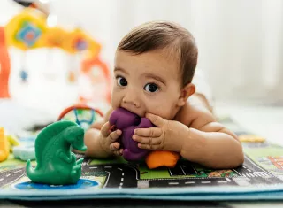 un bébé porte des jouets à sa bouche