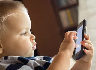 un jeune enfant joue sur un téléphone portable