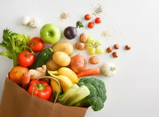 un sac en papier rempli de fruits et légumes sur fond blanc