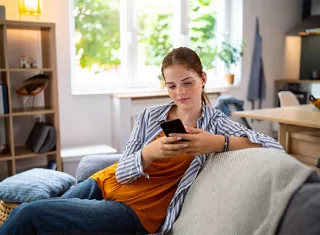 une adolescente sur son téléphone assise dans un canapé